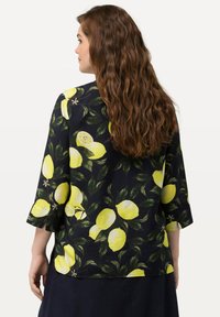 Blusa nera con stampa di limoni gialli e foglie verdi, maniche a tre quarti e vestibilità rilassata con orlo all'altezza dei fianchi.