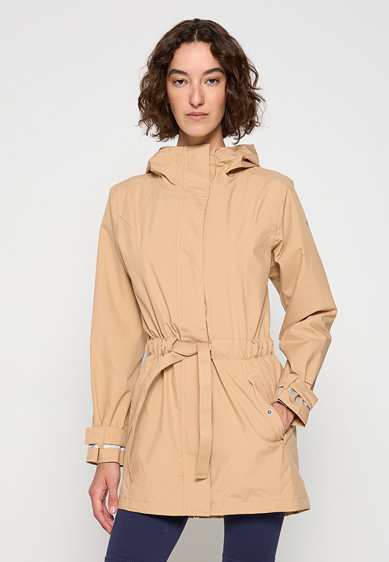 Giacca a vento beige con cappuccio, vita cinchata, polsini regolabili e tasche laterali, realizzata in un tessuto leggero e liscio.