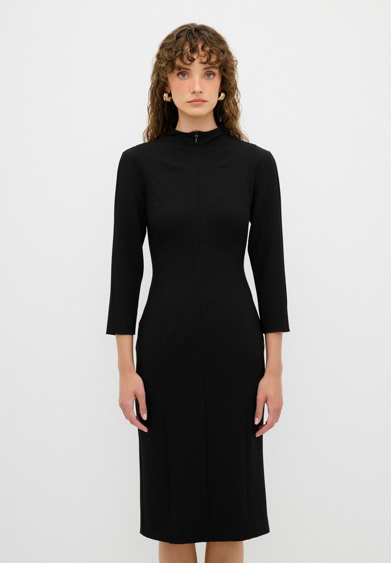 Schwarzes enges Kleid mit hohem Kragen und Dreiviertelärmeln. Glatter Stoff mit einem Reißverschluss vorne und minimalen Nähten, knielang.