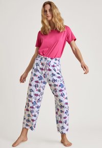 Lichtroze shirt met korte mouwen gecombineerd met witte broek met een kleurrijk vissenpatroon. De broek heeft een elastische tailleband en een trekkoord.