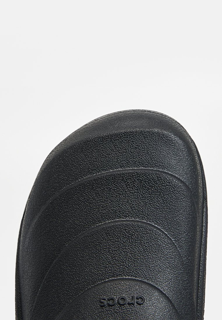 Zwarte Crocs slide sandaal met een gestructureerd oppervlak en horizontale groeven, voorzien van een ronde neus en een lichte constructie.