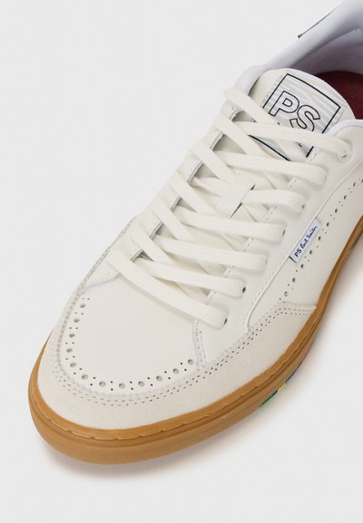 Weiße Ledersneaker mit durchlochentem Zehenbereich, flachen Schnürsenkeln und einer hellbraunen Gummisohle, die bunte Akzente an der Seite aufweist.