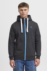 Sweat à capuche gris à fermeture éclair bleu et cordons de serrage. Il dispose d'une poche frontale et d'un petit logo bleu sur la zone de la poitrine gauche.
