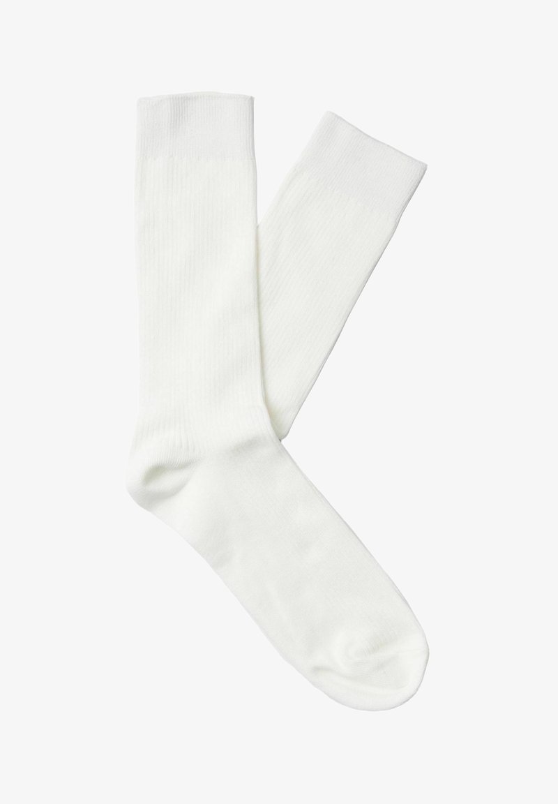 Paire de chaussettes blanches unies de longueur moyenne, posées à plat avec une chaussette légèrement superposée à l'autre sur un fond blanc.