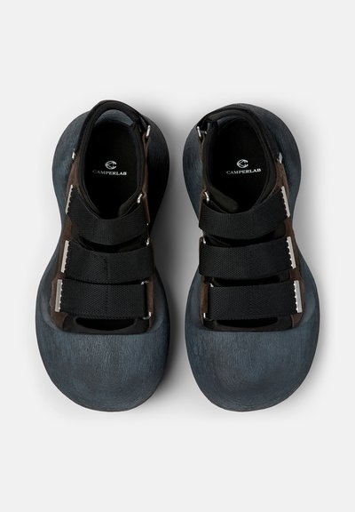 Paire de baskets Camperlab noires et gris foncé avec trois larges bandes Velcro, bout arrondi et semelles rembourrées, vues de dessus.