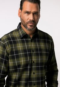 Groen-zwart geruit flanellen overhemd met kraag, knopen aan de voorkant en een zachte textuur. Voorzien van contrasterende witte rasterlijnen.