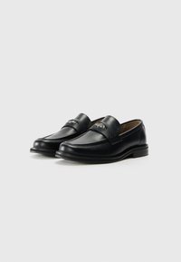 Black leather loafers with a smooth surface, stitched detailing, and a textured band across the top. Features a low heel.