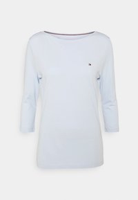 Vaaleansininen naisten pitkähihainen paita, jossa on venepääntie ja pieni Tommy Hilfiger -logo vasemmassa rinnassa.