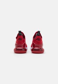 Rote Sportschuhe mit einer glatten, glänzenden Sohle, gepolstertem Obermaterial und schwarzen Akzenten mit einem Logo. Die Rückansicht zeigt ein abgerundetes Fersendesign.