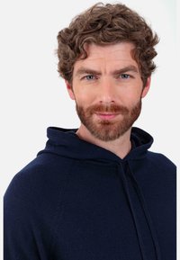 Sweat à capuche bleu marine avec une texture douce et un cordon de serrage. Présente une coupe décontractée et des manches raglan, sans motifs ni accents visibles.