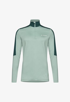 Lichtgroene lange mouw top met een kwart rits, contrasterende donkergroene schouderpanelen en een klein logo op de borst. Zachte, gladde textuur.