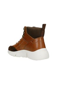 Scarpa alta in pelle marrone con suola spessa bianca, dettagli in camoscio, pannelli in rete e occhielli metallici. Presenta un linguetta sul retro.