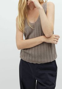 Top in maglia beige con scollo a barca, caratterizzato da un motivo testurizzato e una vestibilità rilassata, abbinato a pantaloni scuri.