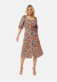 Floral midi dress with orange and blue pattern. Features a square neckline, puff sleeves, and waist tie. Material appears lightweight.