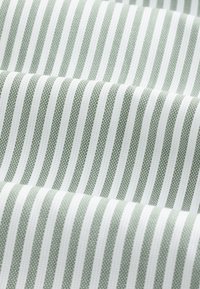 Textilní látka svislými pruhy v zelené a bílé barvě. Textura působí jako tkaná s hladkým povrchem.