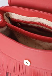 Borsa in pelle rossa con design a frange, hardware dorato e tasca interna con zip. L'interno foderato presenta un motivo con logo in beige.