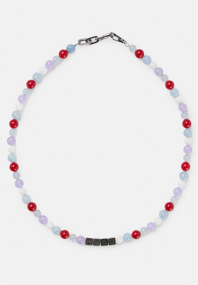 Collier de perles avec des perles alternant en rouge, bleu, violet et blanc, arborant des cubes de lettres noirs formant le mot "HUGO" près d'un fermoir en argent.