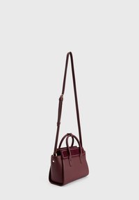Borsa a mano in pelle borgogna con manici superiori e tracolla lunga regolabile, caratterizzata da dettagli in camoscio e cuciture bianche sulla tasca frontale.
