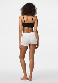Melnā bralete ar plānām siksniņām kombinācijā ar baltām bezšuvju šortiem. Gluda tekstūra, brīva piegriezuma un minimālistisks dizains.