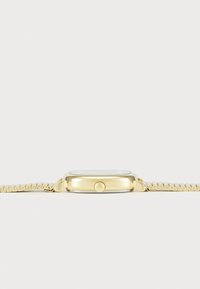 Montre dorée avec un boîtier rectangulaire, un cadran blanc et un bracelet en maille. Elle présente une couronne simple et une finition polie.