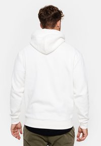 Sudadera blanca con una textura suave, que presenta una capucha con cordón, puños y dobladillo acanalados, mostrada desde la parte posterior con un diseño sencillo.