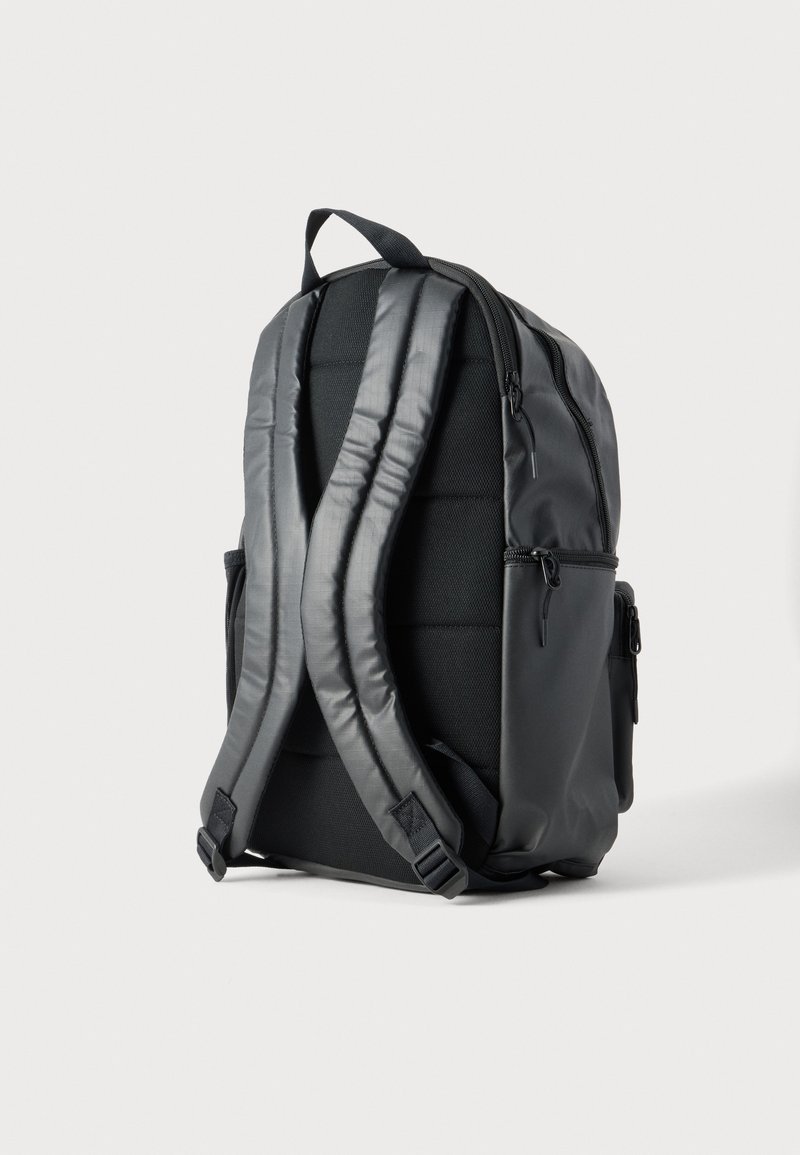 Black backpack with padded shoulder straps, side zippered pockets, and a top carry handle shown from the back on a plain background.