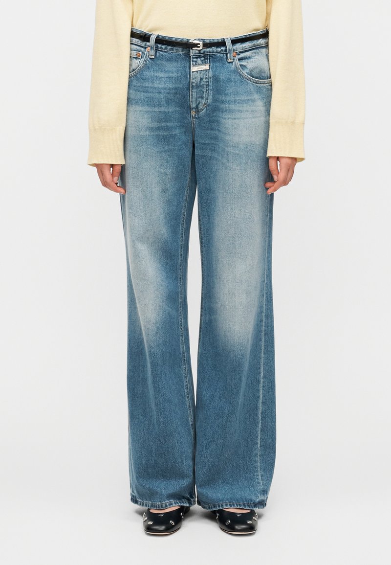 Jeans de pierna ancha azul claro con lavado desgastado, diseño de cinco bolsillos y cinturón negro. Diseñados para un ajuste relajado, con los bajos doblados.