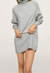 Robe-pull à col roulé oversize gris avec poignets et ourlet côtelés, dotée d'une fente latérale pour une coupe décontractée. Tissu en maille douce et texturée.