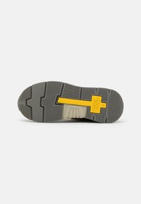 Shoe outsole with a textured gray rubber bottom, featuring a yellow accent and a segmented design for grip and stability.