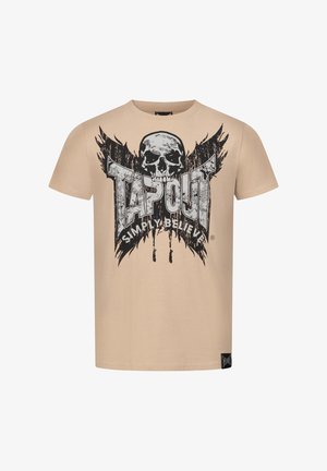 Beige puuvillapaita, jossa on musta pääkallo grafiikka ja "TAPOUT"-teksti. Edessä on kuluneitaefektejä ja abstrakteja siipimäisiä kuvioita.