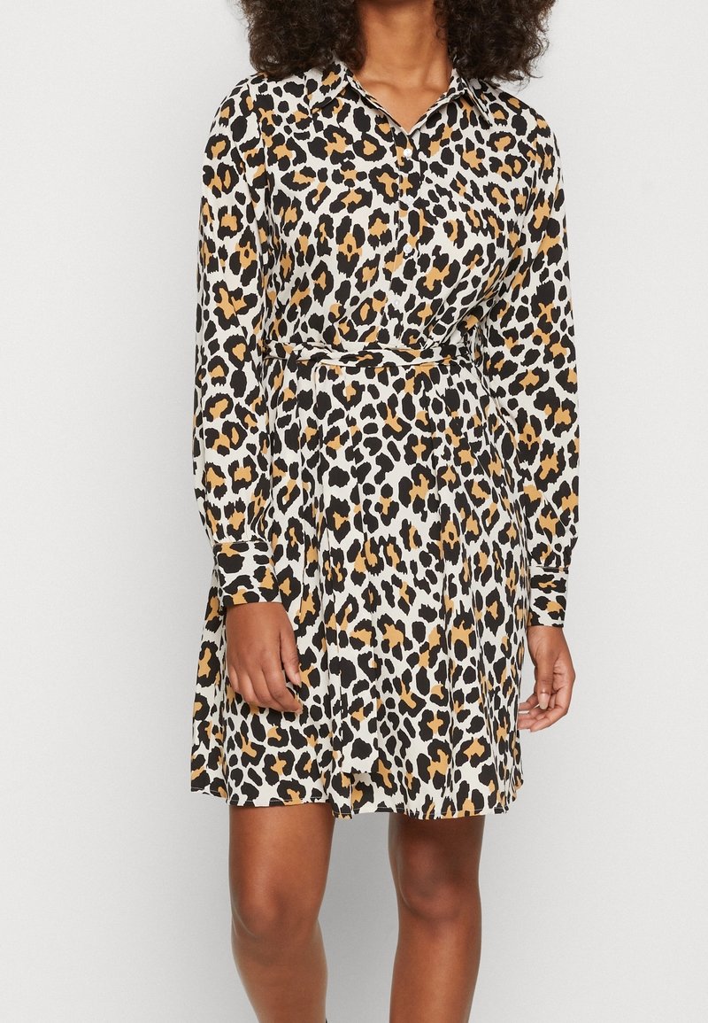 Robe à imprimé léopard avec des manches longues, un devant boutonné et une taille ceinturée. Comprend des couleurs noire, brune et crème dans un tissu fluide.