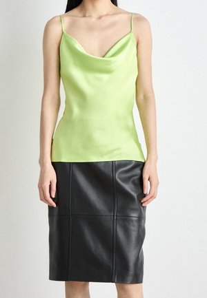 Cowl neck top in bright lime green satin, paired with a fitted black leather skirt featuring seam detailing. Smooth texture and adjustable straps.