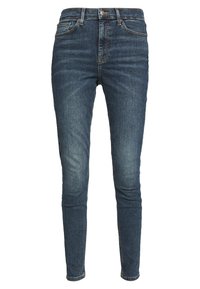 Jean skinny bleu foncé avec taille haute, légères d’étoupes sur les cuisses, design traditionnel à cinq poches et fermeture par bouton.