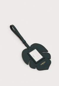Mørkegrøn læder bagagetag formet som et blad, med en klar kortlomme, guld branding og en løkke til fastgørelse.