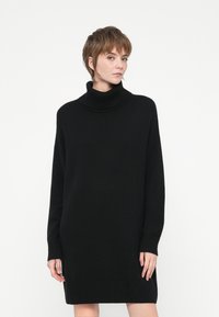 Crna oversized haljina s turtleneck izrezom, pletiva, dugi rukavi, rebrasti rukavi i donji rub, opušteni kroj, mekana tkanina.