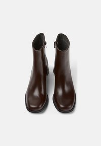 Paire de bottines en cuir brun foncé avec fermetures éclair latérales et bouts carrés arrondis, présentées sur un fond blanc.