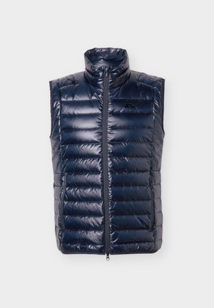 Mørkeblå polstret vest uden ærmer med opretstående krave, lynlås foran, sidelommer med lynlås og diskret logo på brystet.