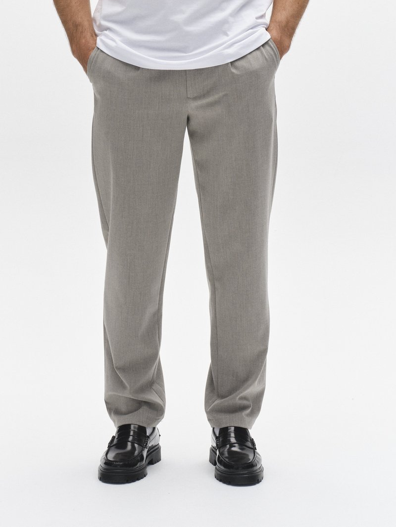 Ljusgrå skräddarsydda byxor med en subtil struktur, med rak benform. Kombinerade med svarta blanka skor.