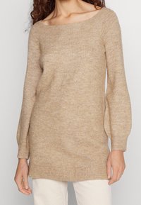 Maglione beige lavorato a maglia con scollatura ampia, maniche lunghe e orlo a coste. Tessuto morbido con vestibilità comoda.