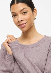 Helllila gestrickter Pullover mit weitem Ausschnitt und gerippten Bündchen, der eine weiche Textur und eine lässige Passform aufweist.