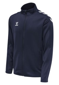 Giacca zip-up blu navy con colletto alto, realizzata in tessuto liscio. Presenta motivo a chevron bianco sulle spalle e tasche laterali.
