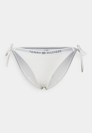Hvit bikinitruse med teksturert stoff, med snører på sidene og en merket linning med "TOMMY HILFIGER"-logo.