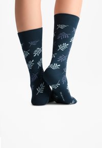 Mornarsko modre nogavice z motivom listov v svetlo zeleni in vijolični barvi; rebrast zaključek in brezšivni prsti za udobje.