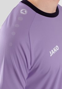Lichtpaarse sportshirt met een zwarte kraag, voorzien van een logo en vijf gestructureerde stippen op de schouder. Gemaakt van een gladde stof.