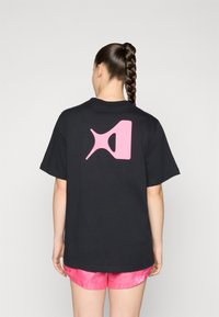 Black t-shirt featuring a large pink graphic design on the back. The shirt has a relaxed fit and is made from soft cotton material.