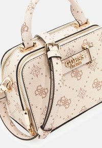 Borsa a mano in pelle beige con motivo logo, hardware dorato, doppie maniglie superiori, tracolla rimovibile e chiusura con cerniera con bordi neri.