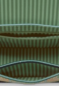 Groene handtas interieur met een gestreept patroon. Glad stof met een ritsvak en contrasterende gestructureerde afwerking langs de rand.