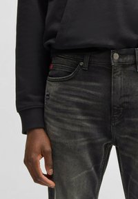 Jeans in denim nero con una finitura consumata, caratterizzati da un classico design a cinque tasche, hardware argentato e un discreto etichetta rossa sulla vita.