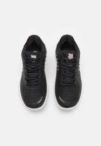 Črne športne čevlje z teksturiranim mrežnim zgornjim delom, oblikovani z rožnatimi poudarki in belim podplatom, z vezalkami in oblazinjenim ovratnikom.