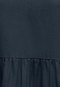 Tissu bleu marine foncé avec des plis froncés créant texture et profondeur sur le matériau.